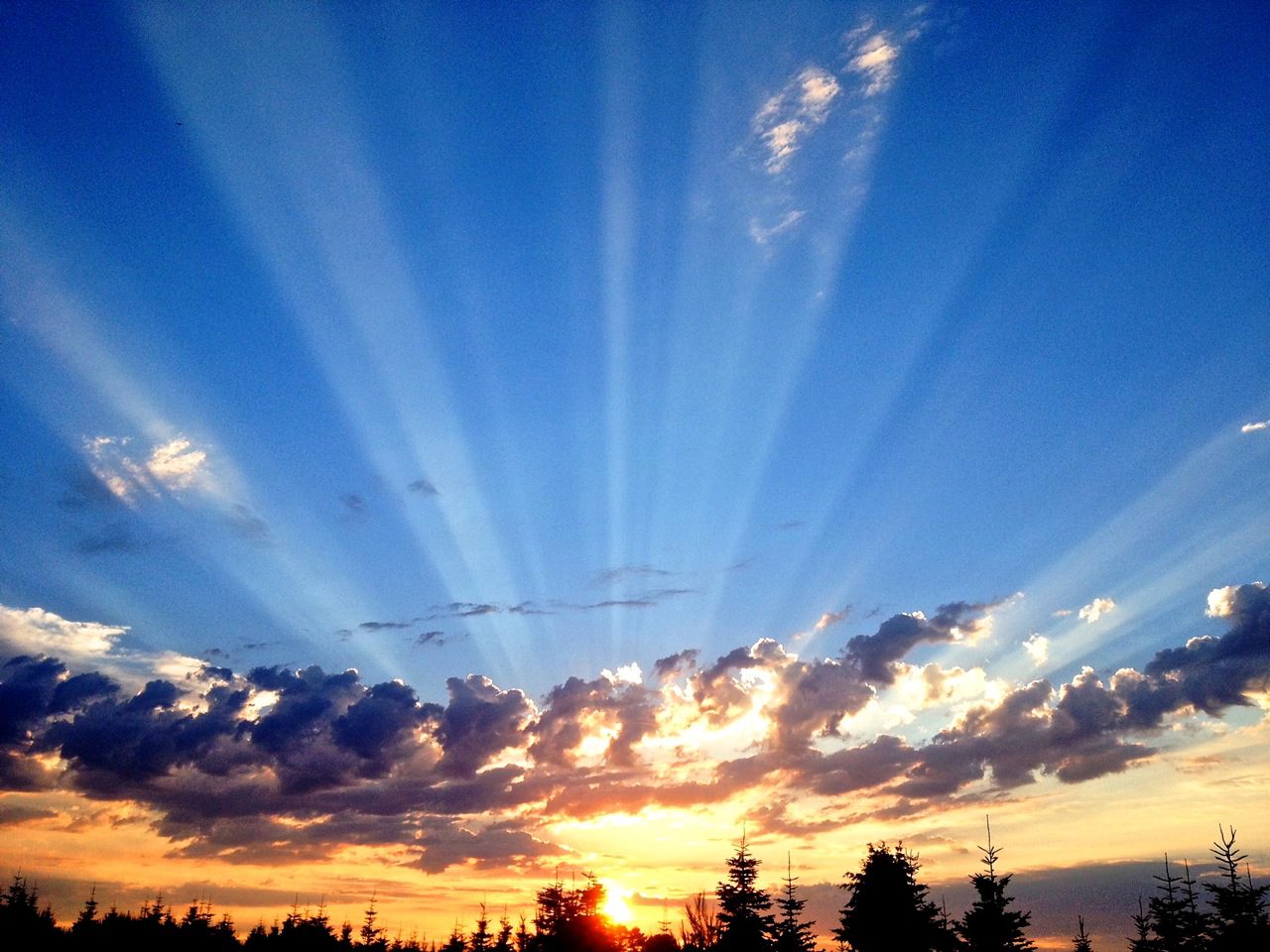 A sunset with the sun shining through clouds.