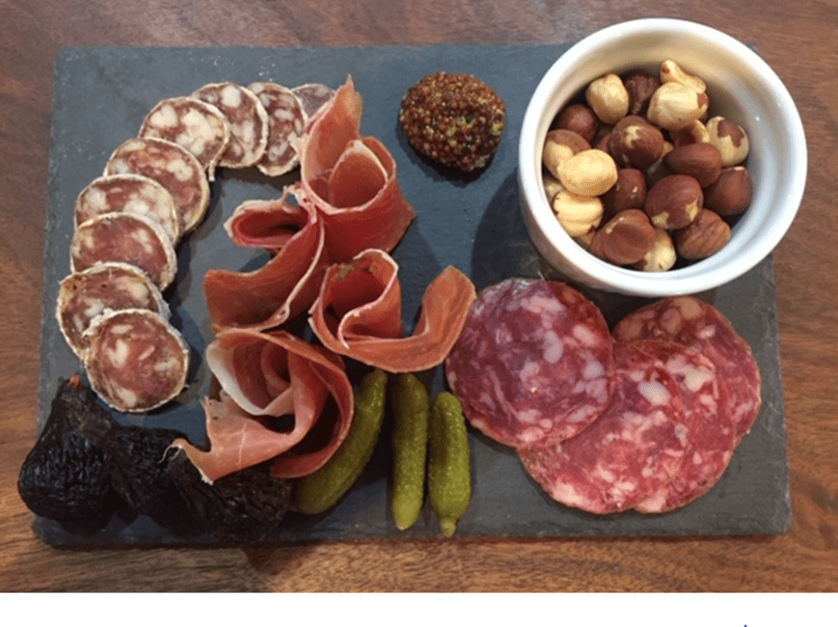 A variety of meats and nuts on a board.