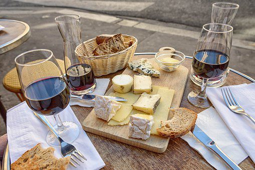 A table with wine glasses and cheese on it