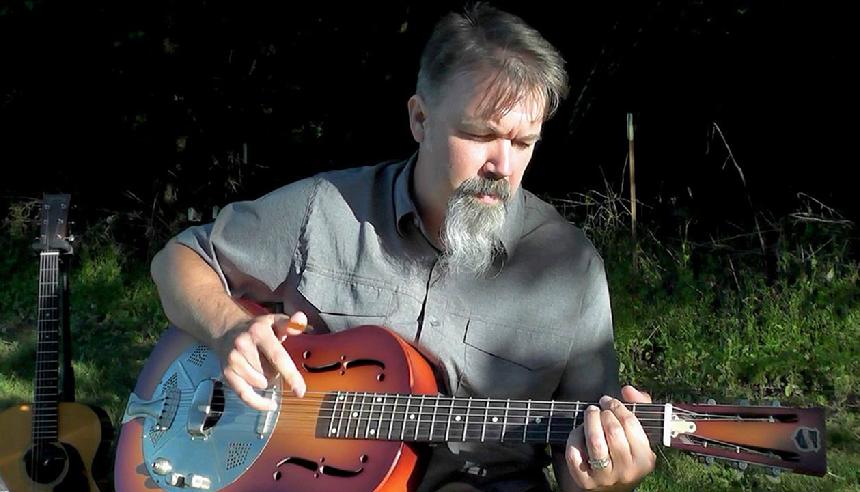 A man playing an instrument in the grass.