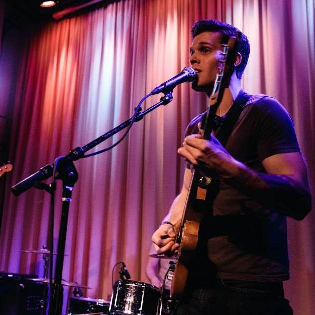 A man playing guitar and singing on stage.