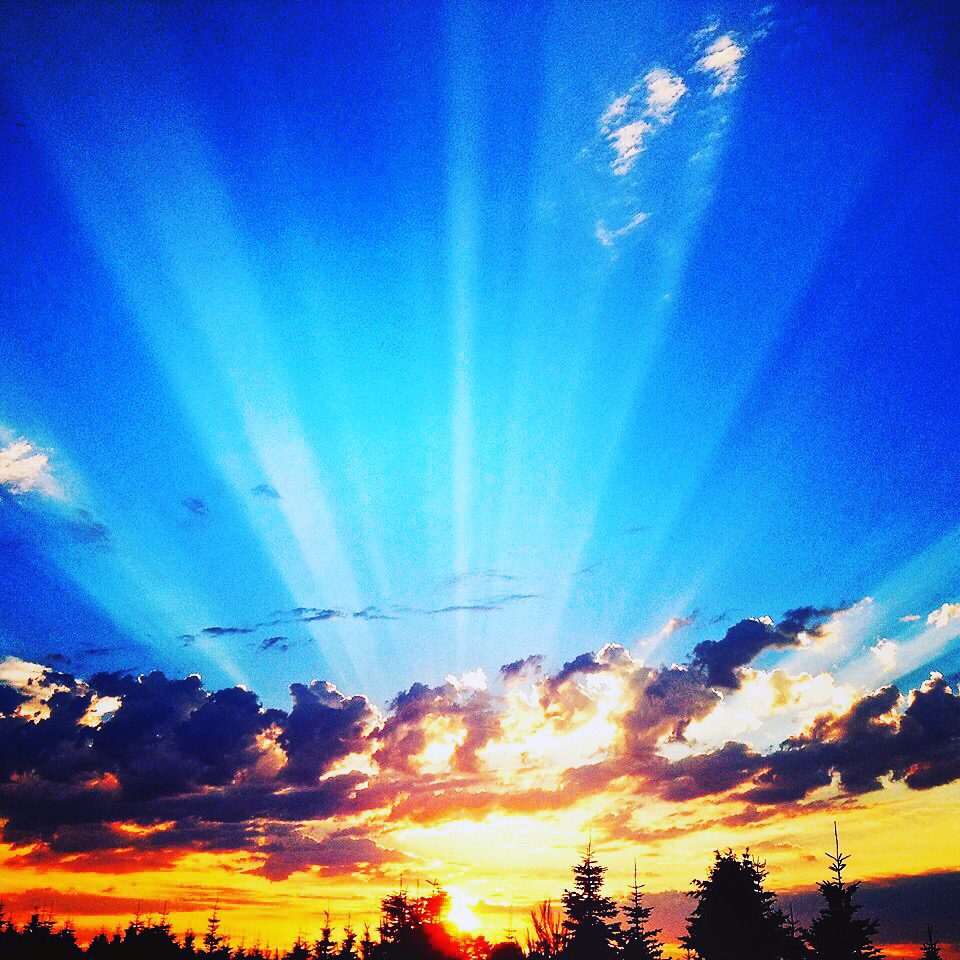 A sunset with the sun shining through clouds.