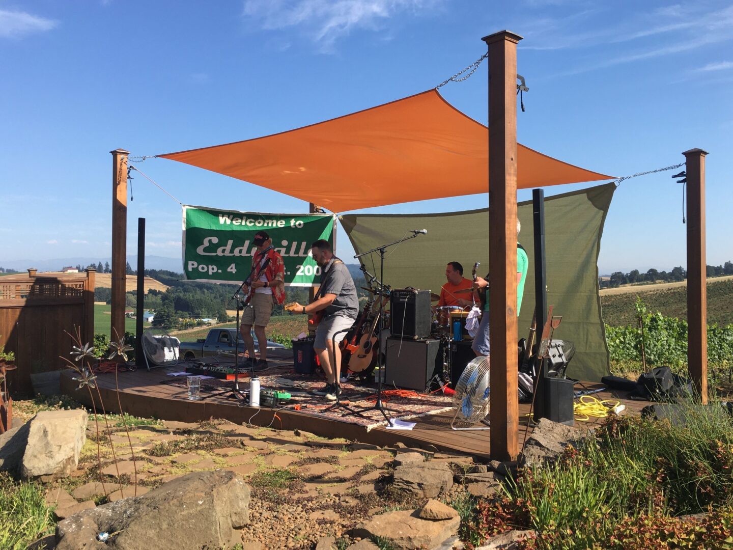 A group of people sitting under an orange tarp.