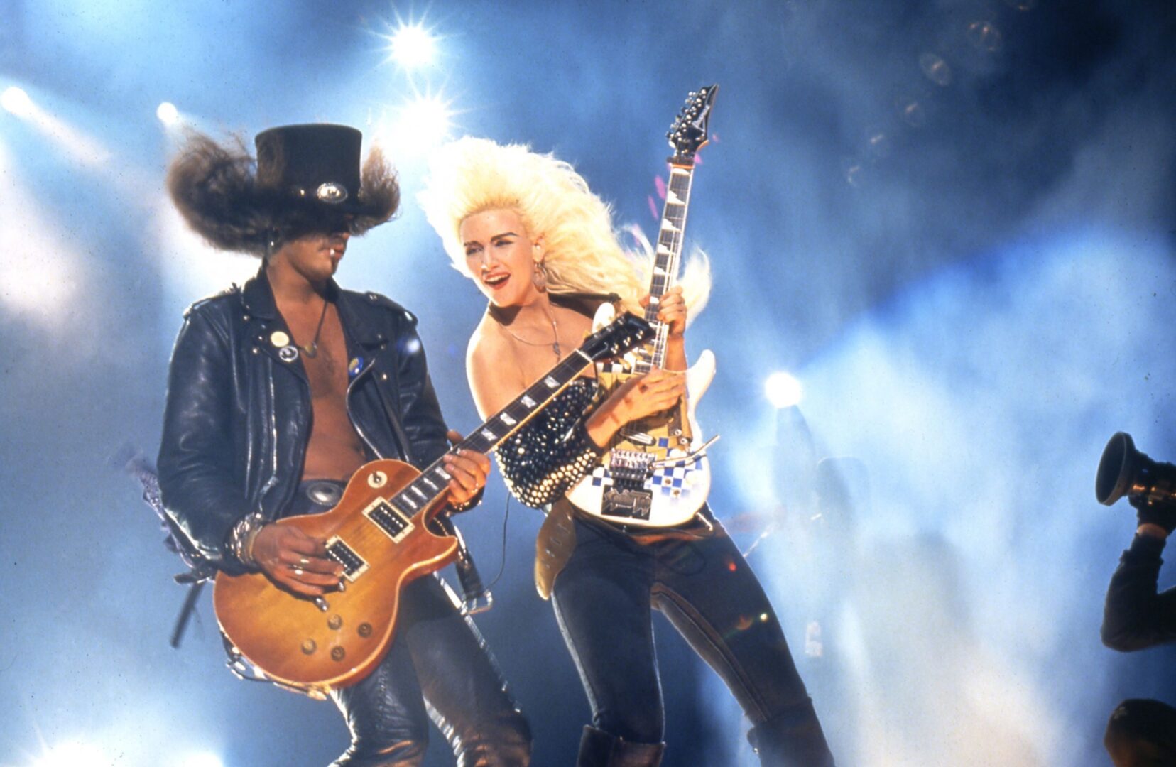 A man and woman are playing guitar on stage.