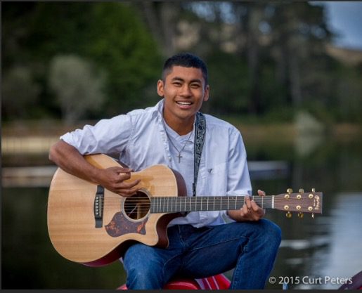 A man sitting on the ground with a guitar.