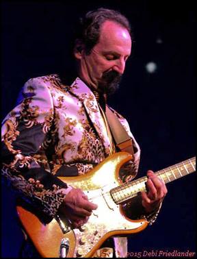 A man playing an electric guitar on stage.