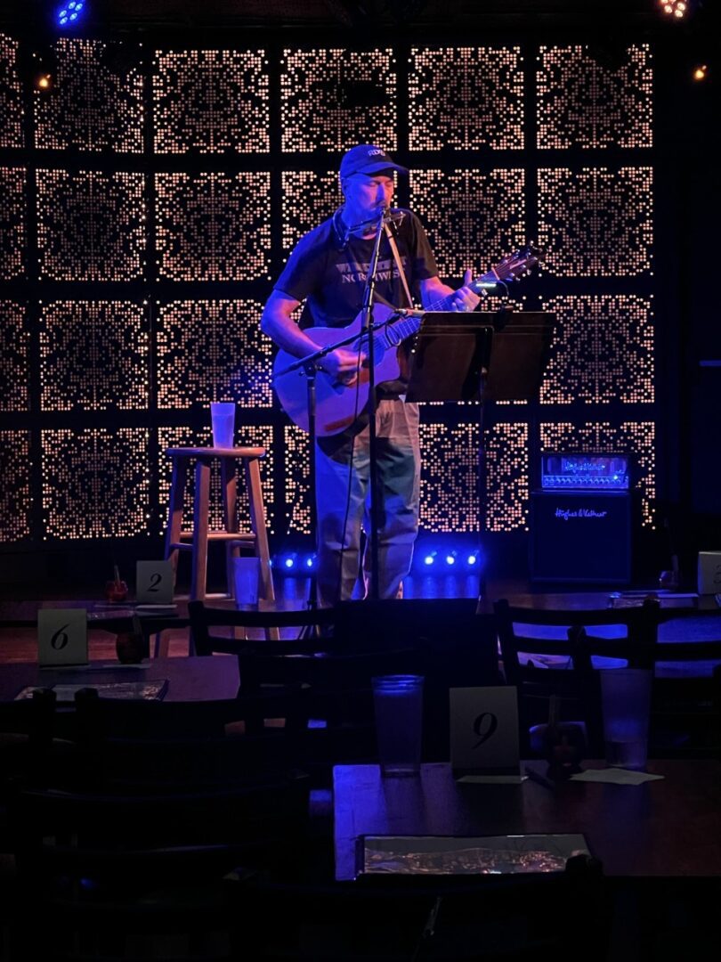 A man playing guitar on stage with musical instruments.