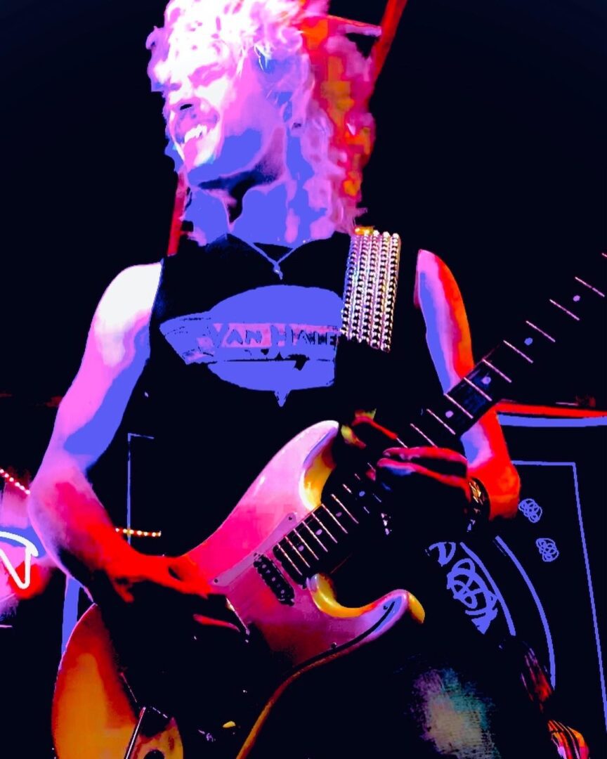 A person with a guitar in front of a crowd.