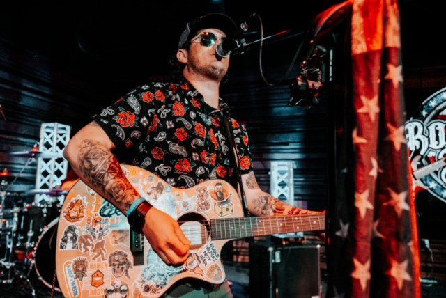 A man with tattoos on his arms playing an instrument.