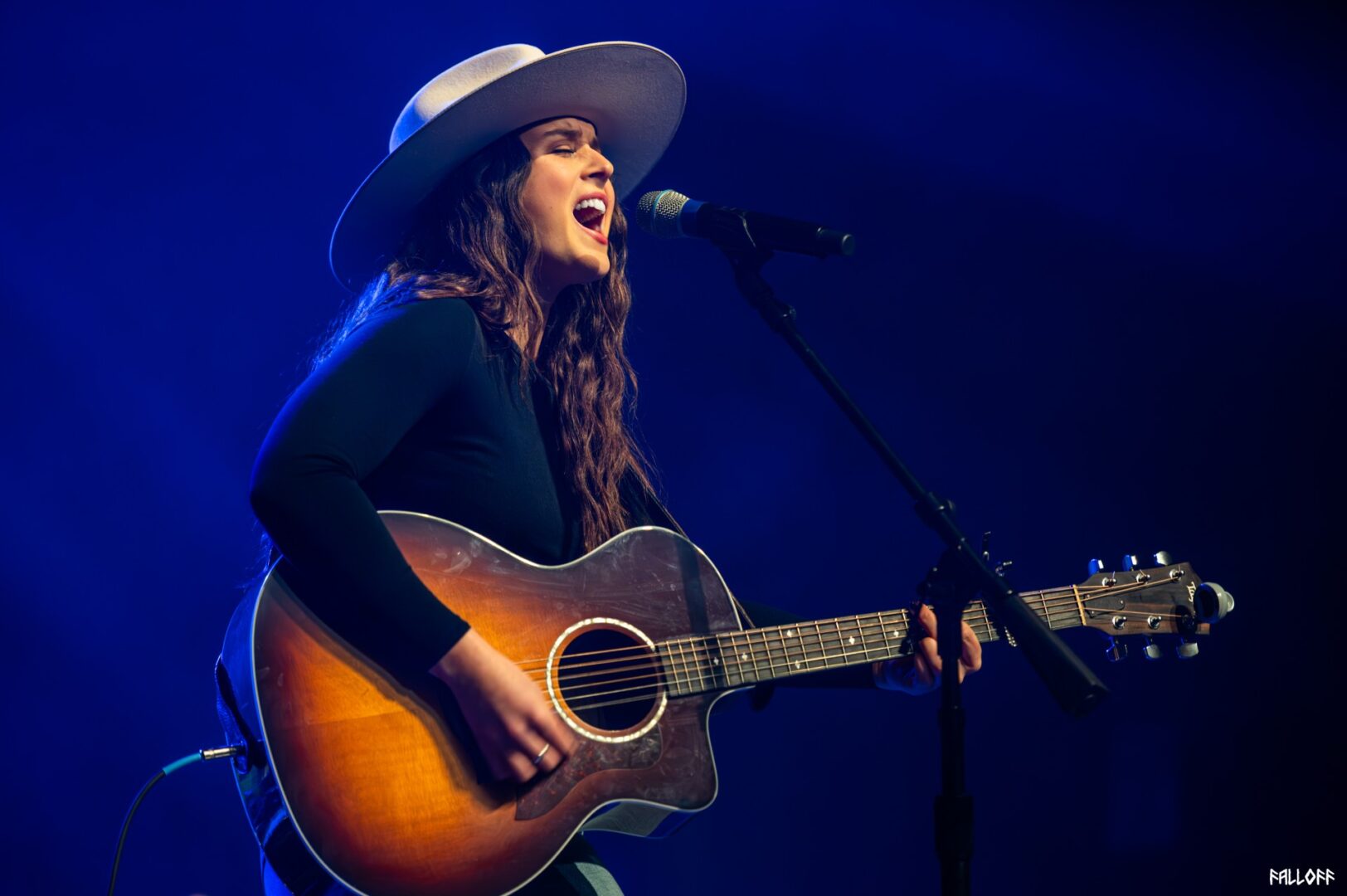 A woman in black shirt playing guitar on stage.