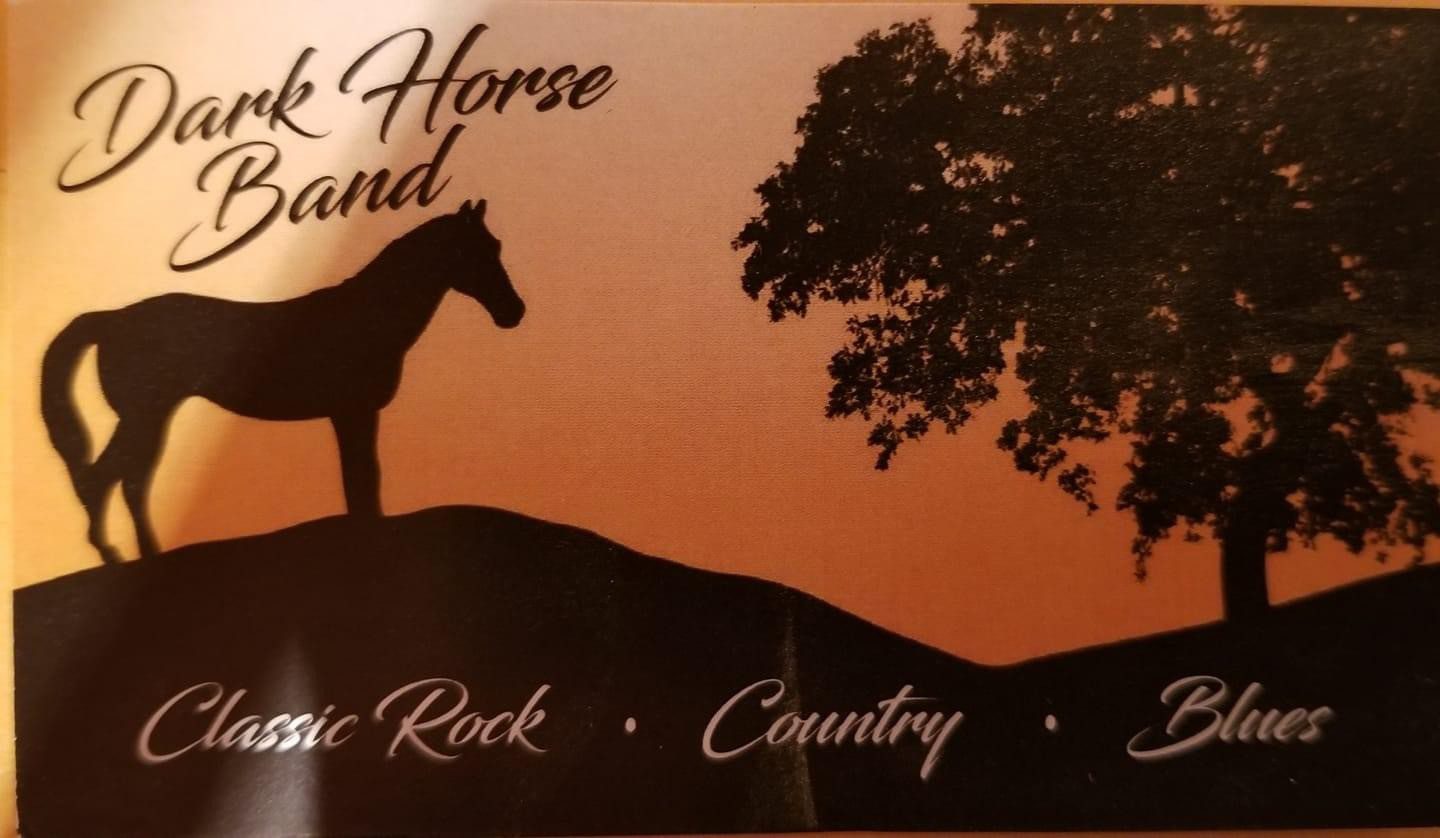 A horse standing on top of a hill next to a tree.