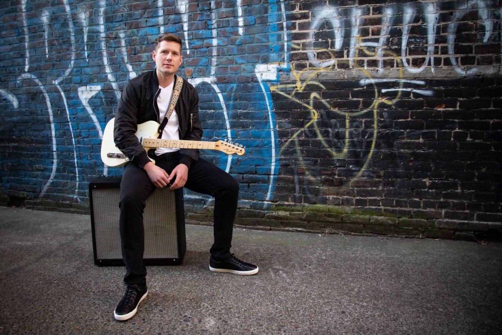 A man sitting on top of a chair holding a guitar.